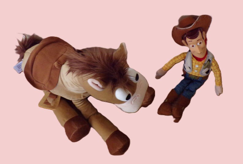 May include: A plush toy set featuring a brown horse and a Woody doll. The horse has a saddle and a brown mane. Woody is wearing a cowboy hat, vest, and boots. The background is a light pink color.
