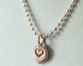 May include: A silver chain necklace with a small, round pendant featuring a heart design.