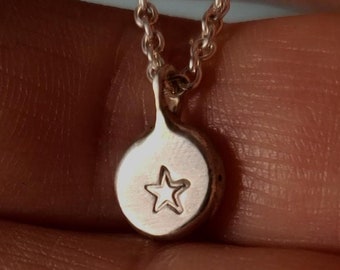 May include: Silver necklace with a small round pendant featuring a star cutout.
