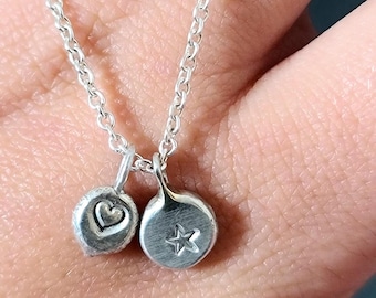 May include: A silver chain necklace with two charms, one with a heart and the other with a star.