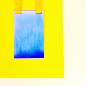 May include: A blue and white rectangular tag with a yellow lanyard attached to the top.