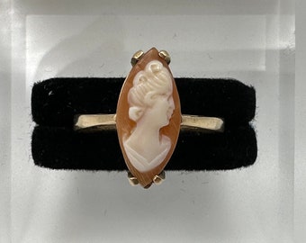 May include: A gold ring featuring a cameo of a woman's profile set in a shell-shaped stone.