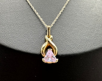 May include: A gold chain necklace with a pendant featuring a pink gemstone set in a gold swirl design.