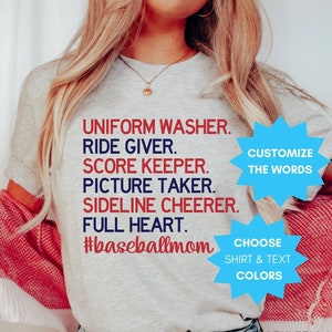 May include: A gray t-shirt with the text "UNIFORM WASHER. RIDE GIVER. SCORE KEEPER. PICTURE TAKER. SIDELINE CHEERER. FULL HEART. #baseballmom" printed on it. There are two blue circles with text on the shirt. The text on the left circle says "CUSTOMIZE THE WORDS". The text on the right circle says "CHOOSE SHIRT & TEXT COLORS". The shirt is on a person wearing blue jeans. The text "ATHLETIC HEATHER PREMIUM TEE" is printed below the shirt.