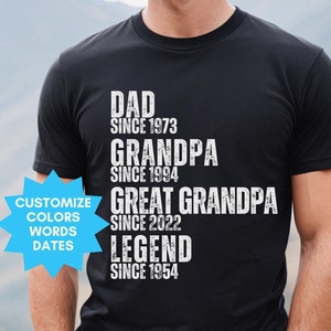 May include: Black t-shirt with white text that reads "Dad since 1973, Grandpa since 1994, Great Grandpa since 2022, Legend since 1954".