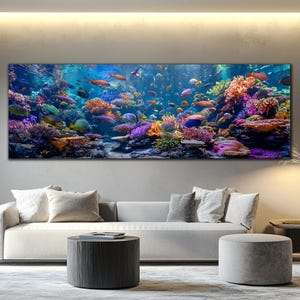 Peut inclure: Une impression sur toile panoramique représentant un récif corallien coloré et animé de poissons variés. L'œuvre d'art présente une riche palette de bleus, d'oranges, de violets et de verts, créant une scène sous-marine vivante. L'impression est affichée au-dessus d'un canapé moderne.