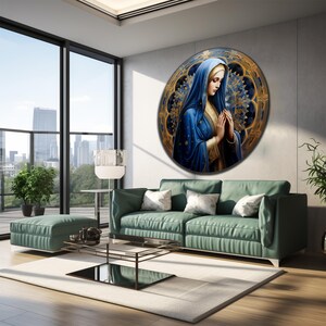 May include: A round painting of a woman in a blue robe with her hands clasped in prayer. The woman is surrounded by a gold and blue mandala design.