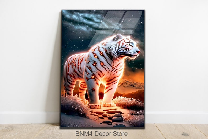 May include: A white tiger with orange stripes stands on a rocky surface. The tiger is illuminated by a bright light, creating a glowing effect. The background is a dark blue sky with stars and a distant mountain range.