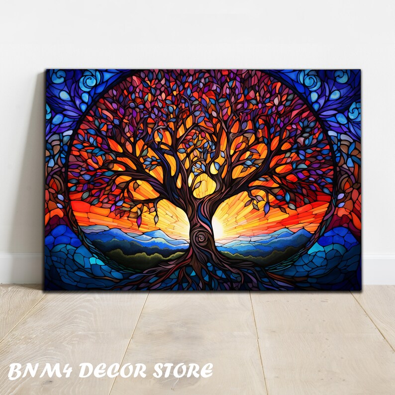 May include: A colorful stained glass style painting of a tree with a sunset in the background. The tree has a thick trunk and many branches with leaves in shades of purple, red, orange, and blue. The sunset is a vibrant orange and yellow with a blue sky above. The painting is framed in a black frame.