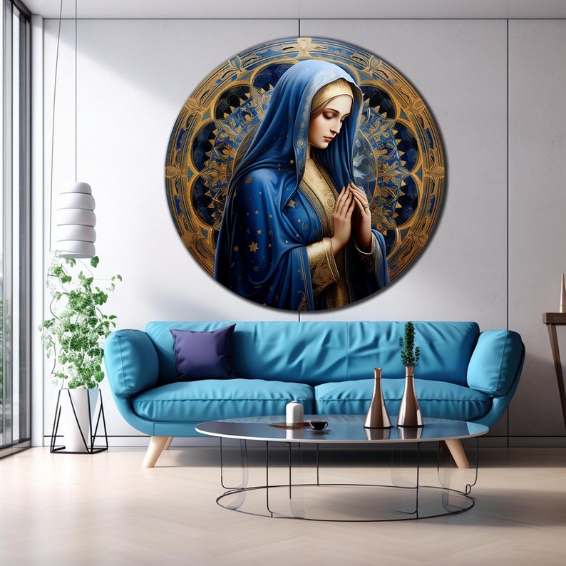 May include: A round canvas print featuring a painting of a woman in a blue robe with a gold halo, praying with her hands clasped. The background is a gold and blue mandala design.