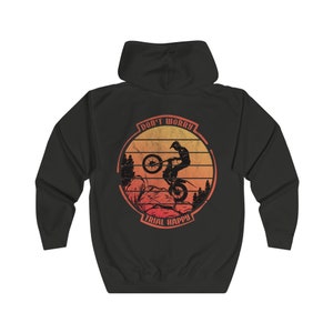 Könnte beinhalten: Schwarzer Kapuzenpullover mit einem Vintage-Grafikdruck einer Person, die ein Dirtbike auf einem Bergpfad fährt. Die Grafik hat einen Sonnenuntergangs-Hintergrund und den Text "Don't Worry Trial Happy".