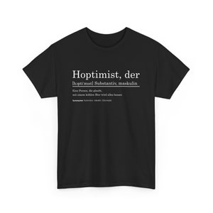 Könnte beinhalten: Schwarzes T-Shirt mit weißem Text. Der Text lautet "Hoptimist, der" mit einer deutschen Definition darunter. Die Definition beschreibt eine Person, die glaubt, dass alles mit einem kühlen Bier besser wird. Synonyme sind unten aufgeführt.