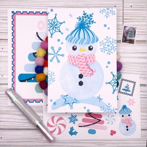 May include: A collection of winter-themed greeting cards and stickers. One card features a snowman with a blue hat and pink scarf. Another card has a Christmas tree design with colorful pom-poms. A silver pen is also included.