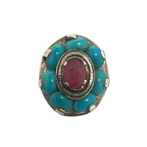 May include: A silver ring with a pink stone surrounded by turquoise stones.