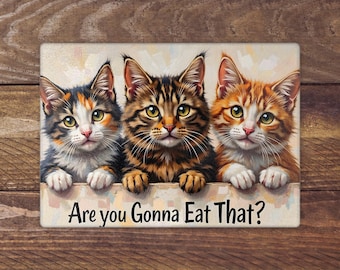 Könnte beinhalten: Rechteckiges Schild mit drei entzückenden Katzen. Die Katzen sind in den Farben Schildpatt, Tabby und Orange. Der Text "Are you Gonna Eat That?" steht darunter in einer verspielten Schriftart.