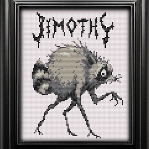 May include: A framed cross-stitch embroidery featuring a stylized, hunched creature with gray fur, a striped tail, and thin black legs. Above the creature, the text JIMOTHY is stitched in a jagged, black, gothic-style font on a white background.