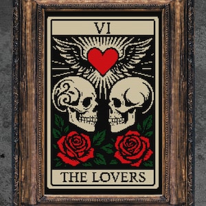 May include: Framed artwork featuring a tarot card design. The card depicts two skulls, a red heart, and roses, with the text "THE LOVERS" at the bottom. The frame is a dark, ornate wood.