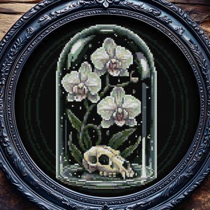 Pode incluir: Uma obra de arte bordada em ponto cruz, emoldurada, com orquídeas brancas numa redoma de vidro e uma caveira na base. A obra está sobre um fundo escuro e emoldurada numa moldura oval preta e ornamentada. O tema é gótico e botânico.