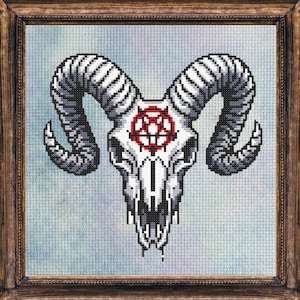May include: Framed cross-stitch art featuring a ram skull with large, curved horns. The skull is white with a red pentagram on the forehead. The horns are gray and white. The artwork is in a dark brown wooden frame.