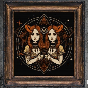 Puede incluir: Obra de arte enmarcada que representa a dos mujeres con cabello rojo y cuernos, sobre un fondo negro. La obra tiene un estilo detallado y pixelado con acentos dorados y marrones, y est&aacute; enmarcada en madera oscura.
