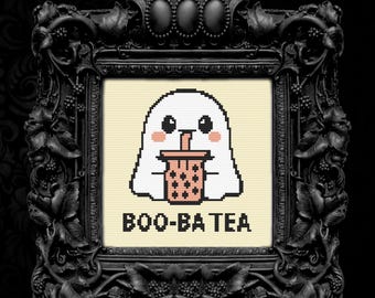 Könnte beinhalten: Kreuzstichkunst eines weißen Geistes, der Bubble Tea trinkt, mit dem Text "BOO-BA TEA" darunter. Das Kunstwerk ist in einem schwarzen, verzierten Rahmen vor einem schwarzen Hintergrund gerahmt. Der Geist hat rosa Wangen und hält einen rosa Bubble Tea.