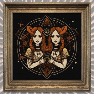Puede incluir: Obra de arte enmarcada con un dise&ntilde;o sim&eacute;trico de dos mujeres con cabello rojo y cuernos, sobre un fondo negro. La obra tiene un marco dorado y detalles intrincados, incluyendo formas geom&eacute;tricas y elementos celestiales. La est&eacute;tica general es g&oacute;tica y m&iacute;stica.