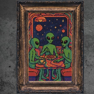Puede incluir: Impresión enmarcada de arte pixelado que representa a tres extraterrestres verdes cenando en una mesa. La escena está ambientada en un entorno similar a un restaurante con un cielo estrellado visible a través de una ventana. La obra de arte está enmarcada en un marco de madera oscuro y ornamentado.