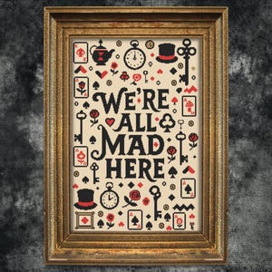 May include: Framed cross-stitch art with the text "WE'RE ALL MAD HERE" in black. The design includes playing card suits, keys, clocks, and a top hat in red and black on a cream background, set in a gold frame.