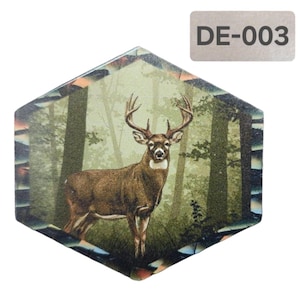 Puede incluir: Un posavasos hexagonal con una escena de bosque que presenta un ciervo de cola blanca de pie en un bosque. El posavasos tiene un patrón de camuflaje alrededor de los bordes.