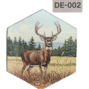 May include: A hexagonal coaster featuring a brown and white deer standing in a field of long grass. The background shows a forest with a blue sky. The coaster has a leather-like texture.