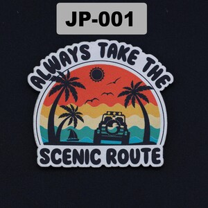 May include: A die-cut sticker featuring a sunset landscape with palm trees, a sailboat, and an off-road vehicle with a duck emblem on the spare tire. The text reads ALWAYS TAKE THE SCENIC ROUTE in black lettering against a white border.
