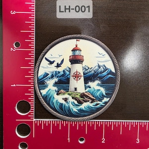 Peut inclure: Un autocollant rond sur le thème nautique représentant un phare avec un toit rouge et des murs blancs, entouré de vagues bleues et d'une rose des vents. Deux oiseaux noirs volent au-dessus d'un ciel bleu avec des nuages blancs. L'autocollant a une bordure en corde et le texte "LH-001" est imprimé au-dessus de l'image.