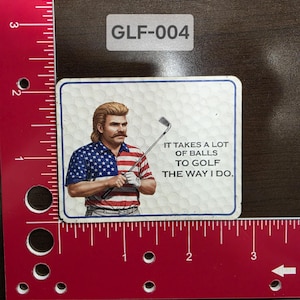 May include: A white square sticker with a cartoon image of a man with a mustache wearing a red, white, and blue shirt and holding a golf club. The text on the sticker reads "It takes a lot of balls to golf the way I do."