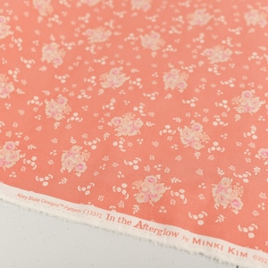 May include: Coral pink fabric with a white floral pattern. The fabric has the text "Riley Blake Designs™ Pattern (C)1372 In the Afterglow by MINKI KIM ©2023 All Rights Reserved" printed on the bottom edge.