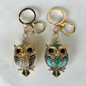 Llavero con diseño de búho brillante, dijes para bolso en verde azulado, negro y blanco, tiradores de cremallera para mochila, colgador de bolso con diamantes de imitación, decoración de diseñador, pájaro adorable, colgante con forma de bujía brillante.