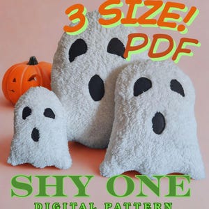 May include: Three plush ghost-shaped pillows of different sizes, with black oval eyes and mouths, are in front of an orange pumpkin. The text "3 SIZE! PDF" is above the ghosts, and "SHY ONE DIGITAL PATTERN" is below.
