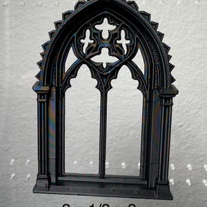 May include: Black gothic-style window with intricate details. The window features an arched top and a decorative pattern. The dimensions are 2 inches by 1/3 inch by 3 inches.