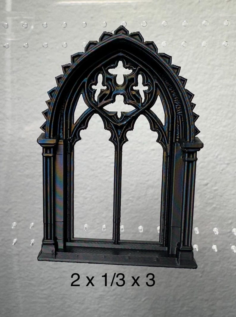 May include: Black gothic window with ornate detailing. The window has an arched top and a decorative design. The dimensions are 5.08 cm x 0.85 cm x 7.62 cm.