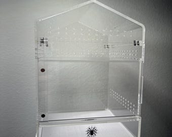 以下が含まれることがあります： 家型の屋根とヒンジ付きドアを備えた透明なアクリルテラリウム。エンクロージャーには換気穴があり、「Heather's Hideaways」のテキストとクモのグラフィックがあります。小型ペット用に設計されています。
