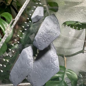 May include: Four gray, textured, 3D printed rocks for a terrarium or reptile enclosure.