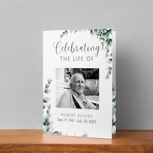 May include: A white card with a green leafy border. The card reads "Celebrating the Life of Robert Davids Sept. 17, 1941 - July 03, 2023". A black and white photo of Robert Davids is in the centre of the card.