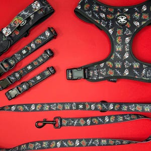 May include: A set of black dog collars and a harness with a tattoo-inspired print featuring butterflies, roses, and daggers. The set includes a leash with the same print.