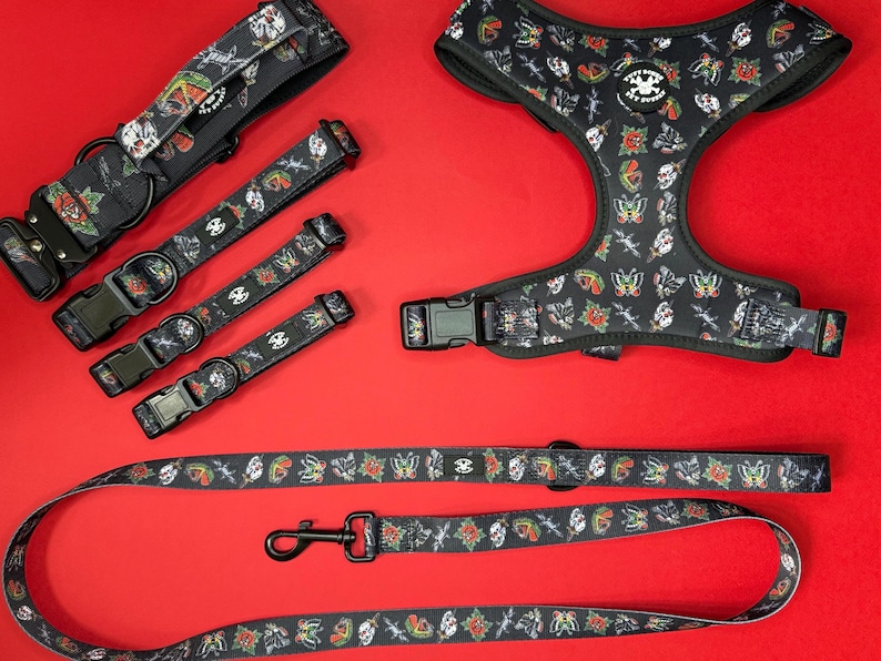May include: A set of black dog collars and a harness with a tattoo-inspired print featuring butterflies, roses, and daggers. The set includes a leash with the same print.