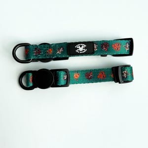 May include: Two green dog collars with black hardware and a repeating pattern of orange and white illustrations. Each collar has a black buckle and a D-ring. The collars have the text "TUFF BONES PET SUPPLY" on a black patch.