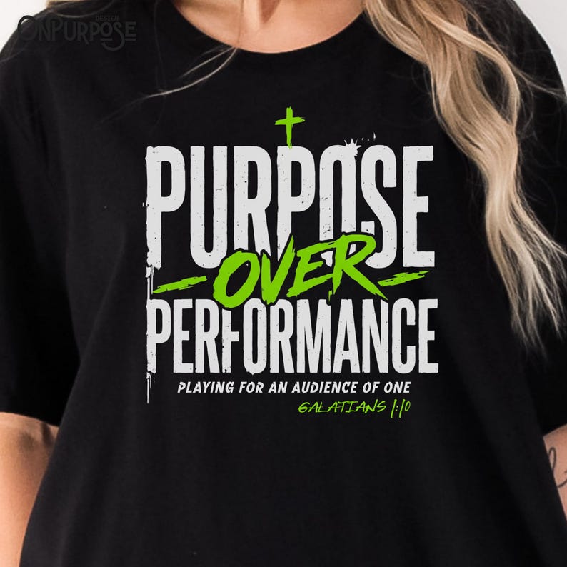 May include: A black t-shirt featuring the white and lime green text "PURPOSE OVER PERFORMANCE" with a small cross above the word "PURPOSE". Below, the text reads "PLAYING FOR AN AUDIENCE OF ONE" and "GALATIANS 1:10" in white and lime green.