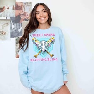 A vibrant and playful baseball-themed design featuring two crossed bats and a baseball, all dripping with colorful icing and sprinkles. The background showcases a bright blue home plate outline, enhancing the bold and energetic look. Perfect for baseball lovers, team logos, and sports-inspired apparel.