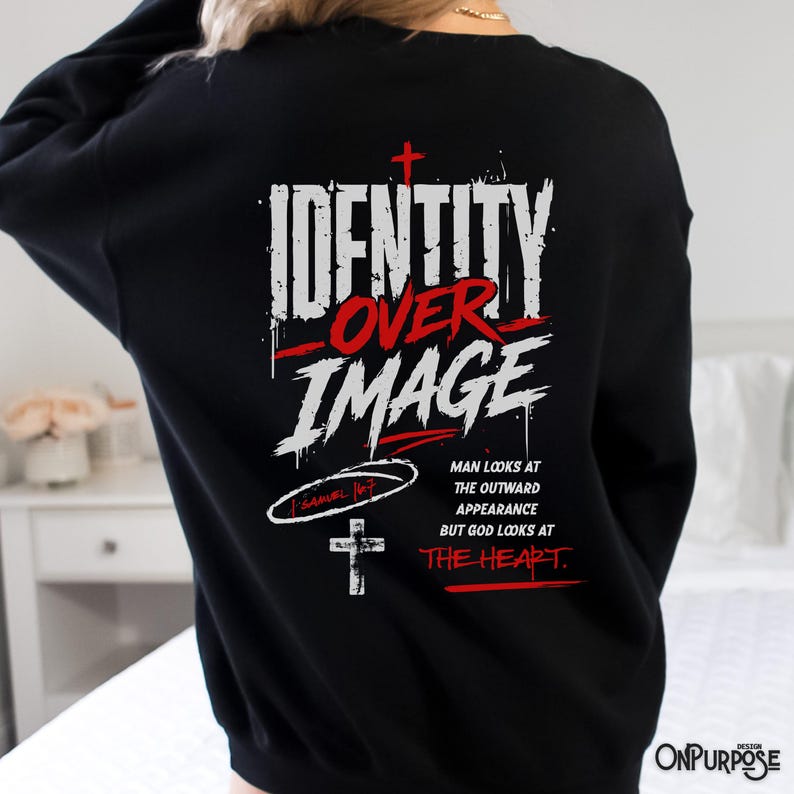 Pu&ograve; includere: Una felpa nera a maniche lunghe con testo grafico bianco e rosso sul retro che recita "IDENTITY OVER IMAGE" con una piccola croce, un riferimento a "1 SAMUEL 16:7" e il testo "MAN LOOKS AT THE OUTWARD APPEARANCE BUT GOD LOOKS AT THE HEART."