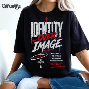 Pu&ograve; includere: Una t-shirt nera con testo grafico bianco e rosso che recita IDENTITY OVER IMAGE. Sotto il testo, include il riferimento biblico 1 Samuel 16:7, una piccola croce e la frase MAN LOOKS AT THE OUTWARD APPEARANCE BUT GOD LOOKS AT THE HEART.