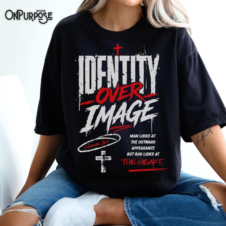 Pu&ograve; includere: Una t-shirt nera con testo grafico bianco e rosso che recita IDENTITY OVER IMAGE. Sotto il testo, include il riferimento biblico 1 Samuel 16:7, una piccola croce e la frase MAN LOOKS AT THE OUTWARD APPEARANCE BUT GOD LOOKS AT THE HEART.
