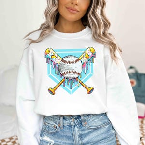 A vibrant and playful baseball-themed design featuring two crossed bats and a baseball, all dripping with colorful icing and sprinkles. The background showcases a bright blue home plate outline, enhancing the bold and energetic look. Perfect for baseball lovers, team logos, and sports-inspired apparel.